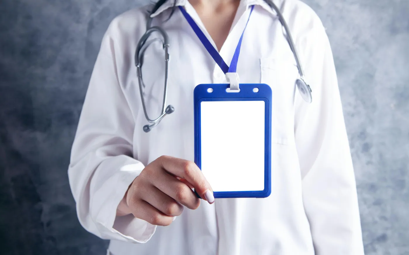 person in white and blue medical scrub holding blue and white card by Sasun Bughdaryan courtesy of Unsplash.