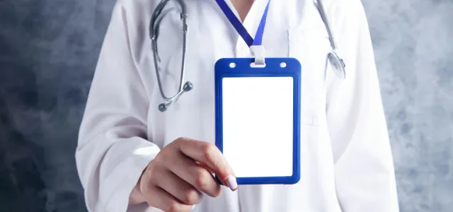 person in white and blue medical scrub holding blue and white card by Sasun Bughdaryan courtesy of Unsplash.